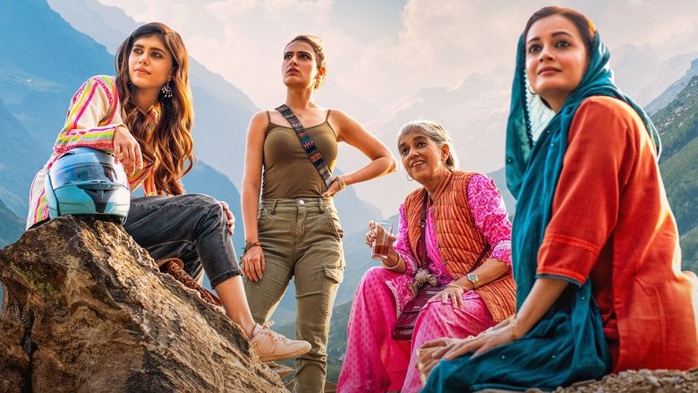Four women on motorcycles pause at a scenic overlook, the Himalayas stretching endlessly behind them