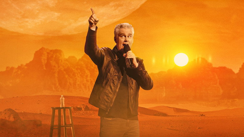 Brian Regan on stage, mid-gesture, with a warm spotlight casting long shadows